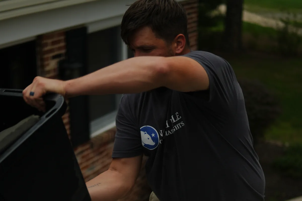 An installer lifting a storage tote at the foot of the ladder, the season packing down